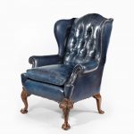 A George I style mahogany wing-arm chair front and side facing blue and brown