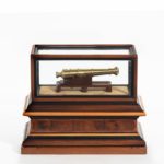 A miniature brass cannon in a presentation case