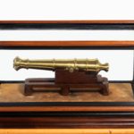 A miniature brass cannon in a presentation case detail