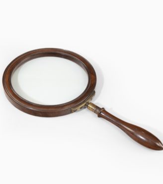 A very large George III gallery magnifying glass, the circular glass within a rosewood frame, the baluster handle screwing into a substantial brass bracket in the rim, inscribed ‘5 L & C’. English, circa 1800.