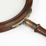 large George III gallery magnifying glass, the circular glass within a rosewood frame, the baluster handle screwing into a substantial brass bracket in the rim, inscribed ‘5 L & C’. English, circa 1800
