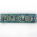 Two Ottoman Iznik border tiles, circa 1600, each of rectangular form, the glazed fritware painted in underglaze turquoise, cobalt blue, black and terracotta red with a continuous band of leafy arabesque scrolls enclosing flowerheads, with turquoise borders mounted Turkish c1600