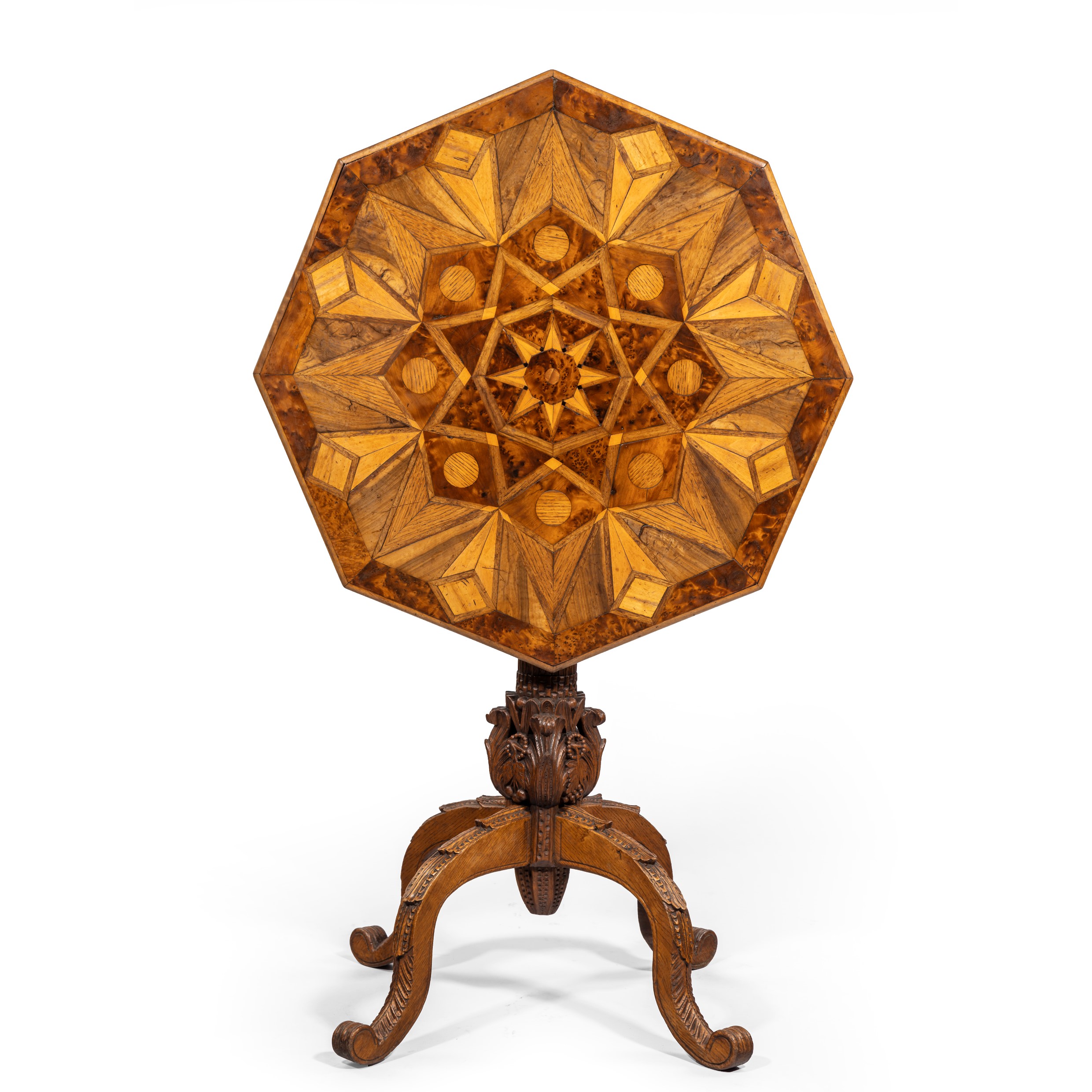 An octagonal indigenous specimen wood marquetry table, the tilt top inlaid on both sides with triangles and diamonds in an overall star design, the woods include yew, oak and elm, on a carved classical column base with four cabriole legs. British, circa 1860.