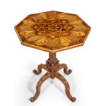 An octagonal indigenous specimen wood marquetry table, the tilt top inlaid on both sides with triangles and diamonds in an overall star design, the woods include yew, oak and elm, on a carved classical column base with four cabriole legs. British, circa 1860.