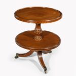 A William IV two tier mahogany table attribruted to Gillows, with two circular shelves, the top one with a dished edge, supported on a reeded and turned baluster column, all on three splayed reeded legs with brass caps and castors