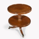 A William IV two tier mahogany table attribruted to Gillows, with two circular shelves, the top one with a dished edge, supported on a reeded and turned baluster column