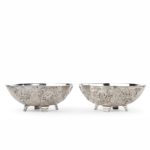 A pair of Meiji period solid silver bowls by Eigyoku, each of lobed oval form on four scroll feet, deeply embossed with continuous chrysanthemum heads and leaves