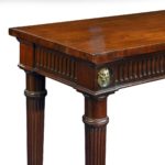 A large Regency mahogany serving table attributed to Gillows, the shaped top above a fluted frieze with four superb ormolu lion’s mask roundels, all raised on six slender, tapering reeded legs - corner