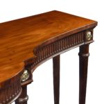 A large Regency mahogany serving table attributed to Gillows, the shaped top above a fluted frieze with four superb ormolu lion’s mask roundels, all raised on six slender, tapering reeded legs detail