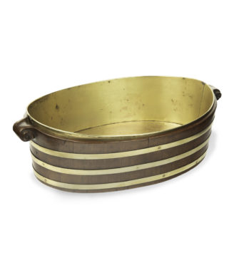 A late Georgian brass bound mahogany oyster bucket, of oval form with three brass bands, wooden volute handles and the original brass liner. English, 1810.