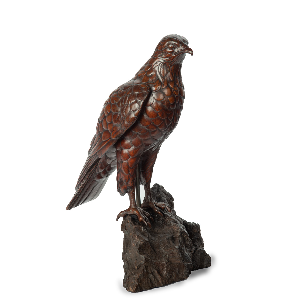 A Black Forest linden wood model of a hawk, standing with wings folded, on a rocky outcrop. Swiss, circa 1910.