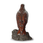 A Black Forest linden wood model of a hawk, standing with wings folded, on a rocky outcrop. Swiss back