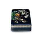 A Meiji period cloisonné box and cover, Ando Company, worked in silver wire and coloured enamels with an array of brightly coloured flowers, reserved against a rich midnight-blue ground, with silver rims and a silk lining, inlaid Ando mark.  Japanese, circa 1910 side