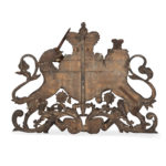 A Victorian carved oak Royal Coat of Arms, the central shield quartered with the three lions England, an Irish harp and a lion rampant surmounted by a crown and supported by the lion and unicorn, with the flowers of the union and motto ‘Dieu et Mon Droit’beneath.  English back